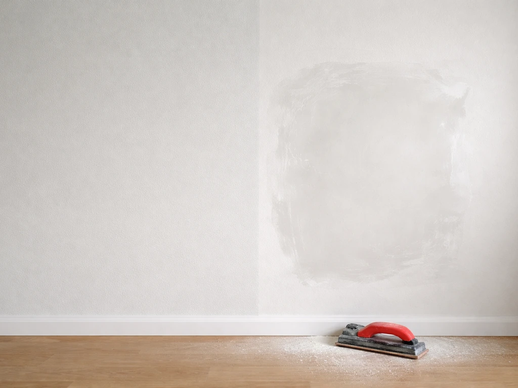 Mur intérieur : zone nettoyée et lissée prête à être posée, avec enduit poncé en cours de préparation.